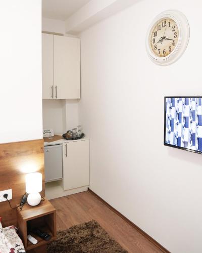 a room with a white wall with a clock on the wall at Apartments Manitovac M in Nikšić