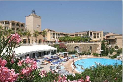 a resort with a swimming pool with people and umbrellas at Le Hameau Cap Estérel in Valescure