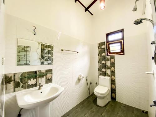 a white bathroom with a sink and a toilet at Lavender Home Yala Safari in Tissamaharama