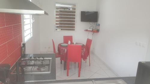 a kitchen with a table with red chairs and a stove at Chez Roberto Bungalow Ayden in Petit-Canal