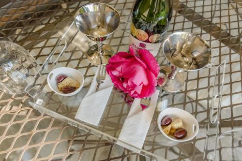 a glass table with plates and glasses and a pink flower at Fleur de Lis Guesthouse in Krugersdorp