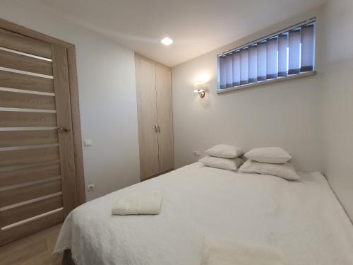 1 dormitorio con 1 cama con sábanas blancas y ventana en S&S Apartments, en Palanga
