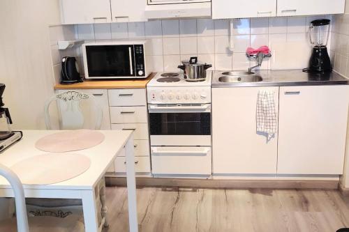 波里的住宿－Viihtyisä yksiö Porissa，厨房配有白色橱柜和炉灶烤箱。