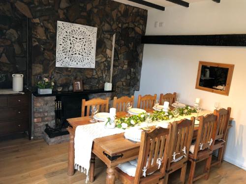a dining room with a table and chairs and a stone wall at Cosy Rustic 3 bed cottage, great train links in Bebington
