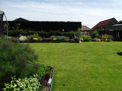 a yard with a green lawn with flowers and plants at Woldview House Bed and Breakfast in Tealby