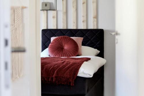 - un lit avec une tête de lit noire et un oreiller rouge dans l'établissement Ferienhaus CLARNI, à Saint-Wendel