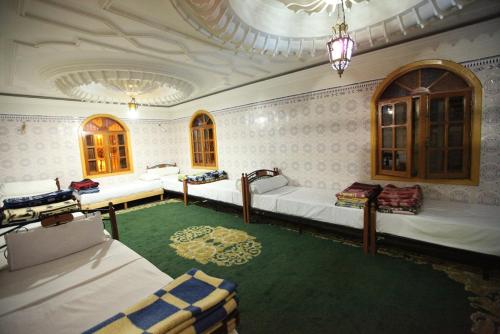 a room with three beds and a green carpet at Auberge Lion de l'Atlas in Azrou