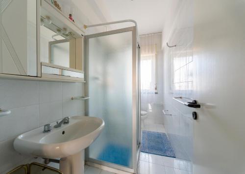 - une salle de bains blanche avec deux lavabos et une douche dans l'établissement Etna Perla Verde, à Fondachello