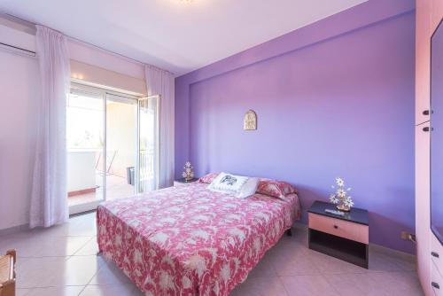una camera viola con letto e finestra di Etna Perla Verde a Fondachello