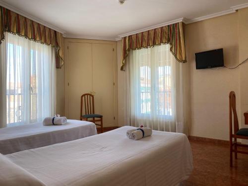 a hotel room with two beds and a flat screen tv at El Pozo de la Nieve in Tordesillas