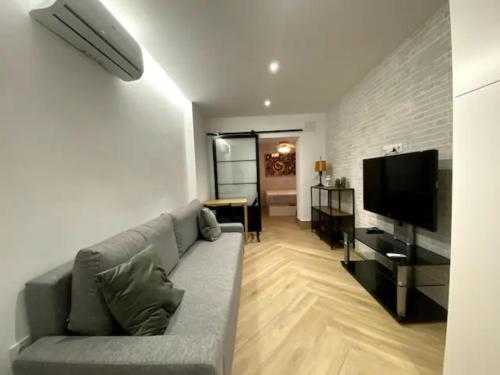 uma sala de estar com um sofá e uma televisão de ecrã plano em coqueto apartamento en Sevilla em Sevilha