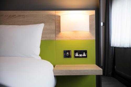 a bedroom with a bed and a green wall at Thistle Express London Luton in Luton