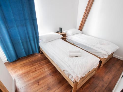 two beds in a room with wooden floors and blue curtains at Dworcowa Centrum Apartament in Bydgoszcz