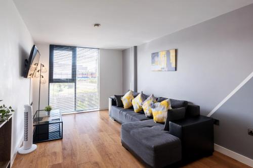 a living room with a black couch and yellow pillows at Lovely 2BR Apt in Sheffield City Centre in Sheffield