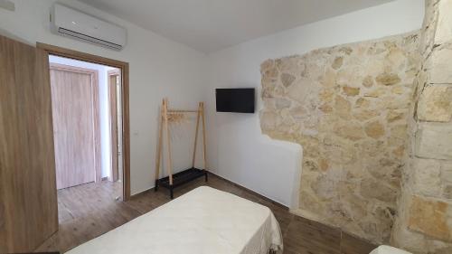 a room with a stone wall with a bed and a television at Elizabeth Suites in Kato Daratso