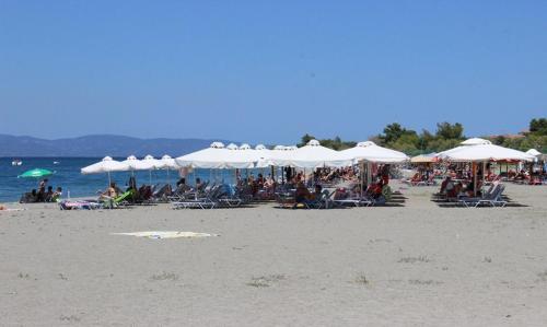 a group of people sitting on a beach with umbrellas at Panorama in Pefki