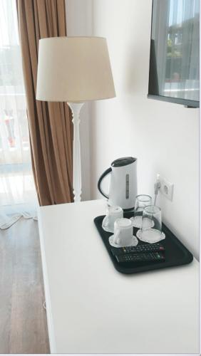 a table with a coffee maker and a lamp on it at Hotel AVENUE in Ravda