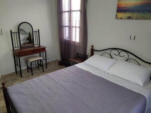 1 dormitorio con cama y escritorio con espejo en Kisiris House, en Mandrákion