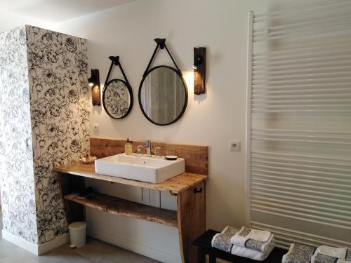 ein Bad mit einem Waschbecken und einem Wandspiegel in der Unterkunft A deux pas de St Cirq Lapopie, La chambre du "cocher" des Murets de L'isa in Esclauzels