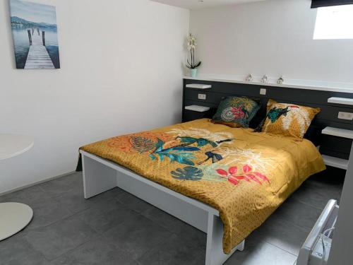 een slaapkamer met een bed met een dekbed en kussens bij Appartement 5 personnes avec accès piscine in Thyle