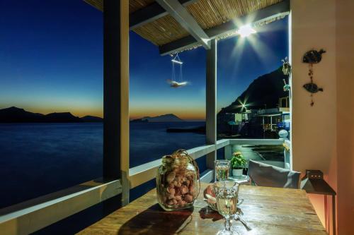 a table with wine glasses and a view of the ocean at Kalimera & Apoplous boathouse in Klima