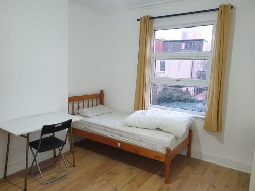 a bedroom with a bed and a desk and a window at Burney Tomar House in Croydon