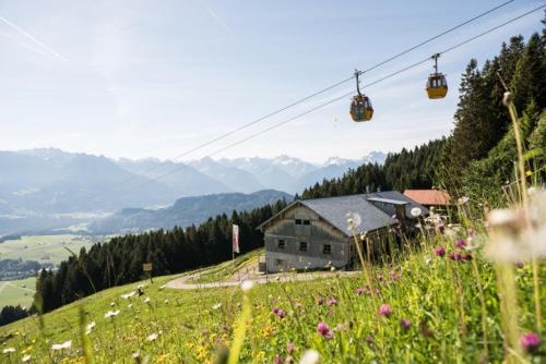 a mountain with a house and a ski lift at Landhaus Bergidyll - Ferienwohnung Kapellenblick in Bolsterlang