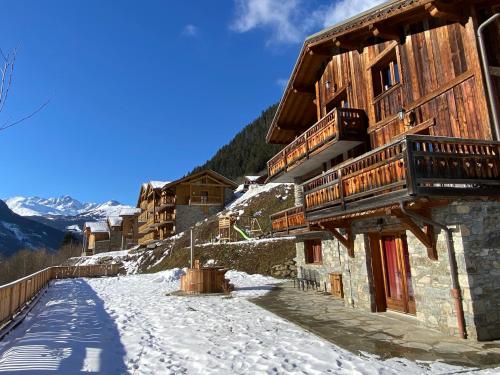 a building with snow on the ground next to a mountain at Chalet des Trappeurs Coeur Vanoise 15 persons in Champagny-en-Vanoise