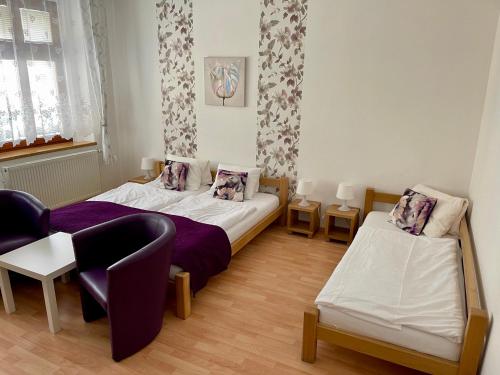 a bedroom with two beds and a couch and a chair at Penzion u Vlčků in Cheb