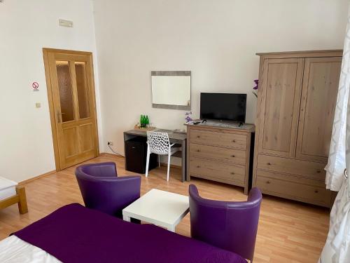 a bedroom with purple chairs and a desk with a tv at Penzion u Vlčků in Cheb