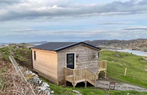 ein kleines Haus auf einem Hügel mit einer Terrasse in der Unterkunft Sea View Cabin in Clashnessie