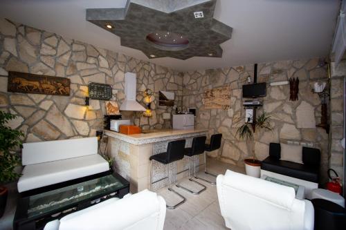 a living room with a stone wall with two white chairs at Mejić Apartments in Kotor