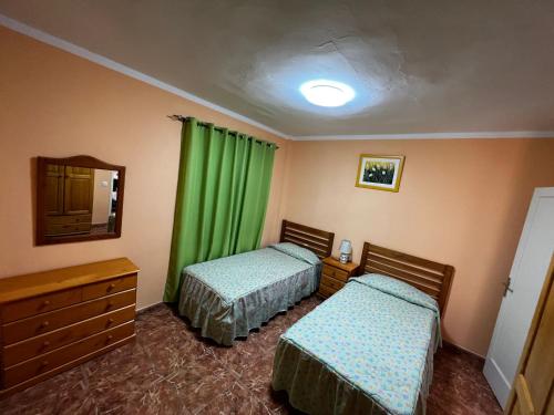 two beds in a room with green curtains at Casa Blanca in Alojera