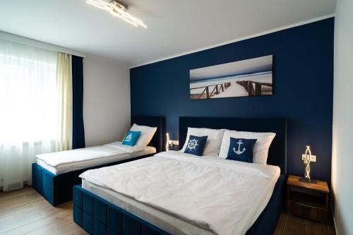 a bedroom with two beds with blue walls at Apartament Zielony Przylądek in Brwinów