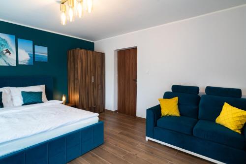 a bedroom with a blue bed and a couch at Apartament Zielony Przylądek in Brwinów