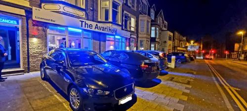 a row of cars parked on a street at night at The Avari Beach Hotel in Blackpool