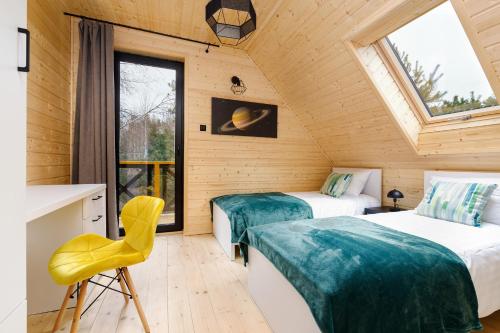 a room with two beds and a yellow chair at Planeta 66 in Olsztynek