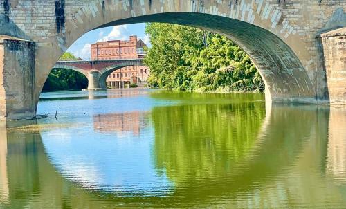 un pont sur une rivière avec un bâtiment en arrière-plan dans l'établissement Moulin d'Albias aux portes de Montauban, à Albias