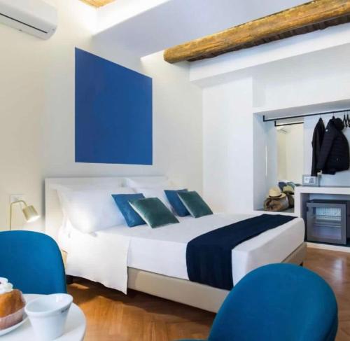 een slaapkamer met een bed en twee blauwe stoelen bij Euphoria al Duomo in Napels