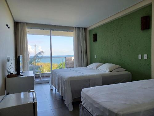 a hotel room with two beds and a view of the ocean at Pousada Laguna in Jacumã