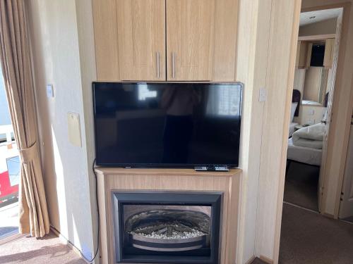 a flat screen tv sitting on top of a fireplace at PG174 Golden Palm Resort 8 Berth Caravan With Decking in Chapel Saint Leonards