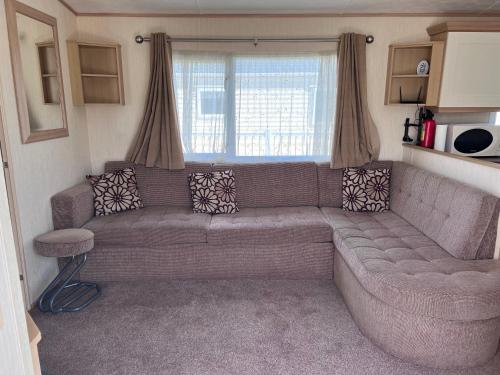a living room with a couch and a window at PG174 Golden Palm Resort 8 Berth Caravan With Decking in Chapel Saint Leonards
