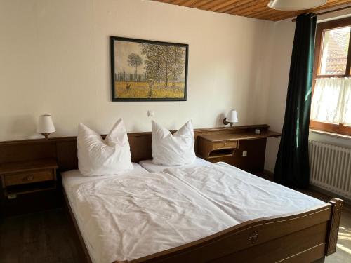 a bedroom with a bed with white sheets and pillows at Pension Main-Art in Mainstockheim