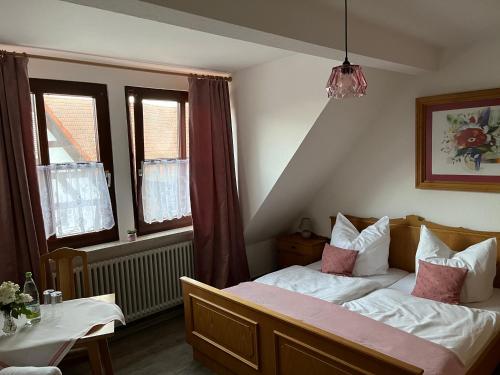 a bedroom with a bed and two windows at Pension Main-Art in Mainstockheim
