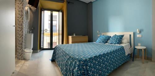 1 dormitorio azul con 1 cama con edredón azul en Baobab Hostal, en El Puerto de Santa María