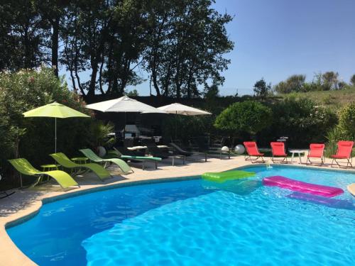 a swimming pool with chairs and umbrellas in a yard at VILLA LES YUCCAS - Pool - Sea view in Cagnes-sur-Mer