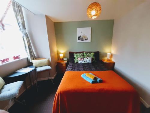 a bedroom with a bed with a orange blanket and a chair at aabAlree Guest House in Dundee