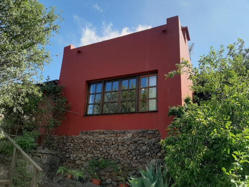 a red house with a stone wall at FINCA EL PEDREGAL in Valsequillo