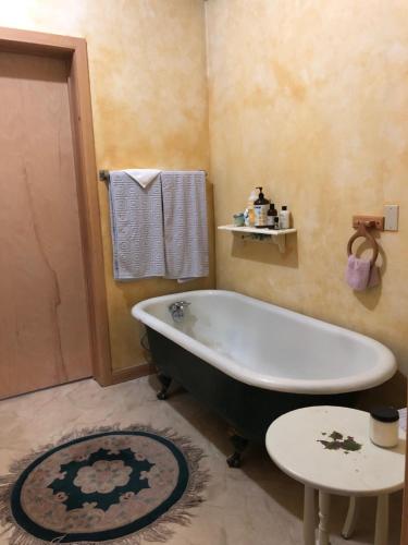 y baño con bañera, mesa y alfombra. en China Bend Winery Bed and Breakfast, en Kettle Falls