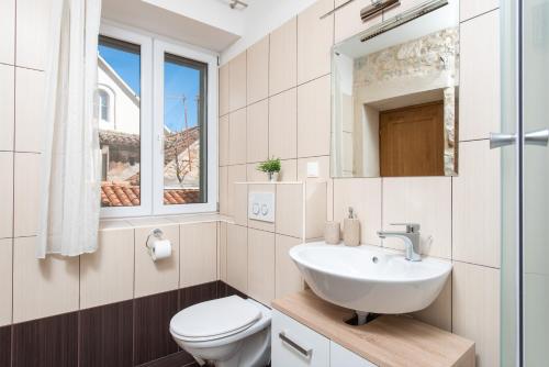een badkamer met een wastafel, een toilet en een raam bij Dolce Vita Apartments in Split
